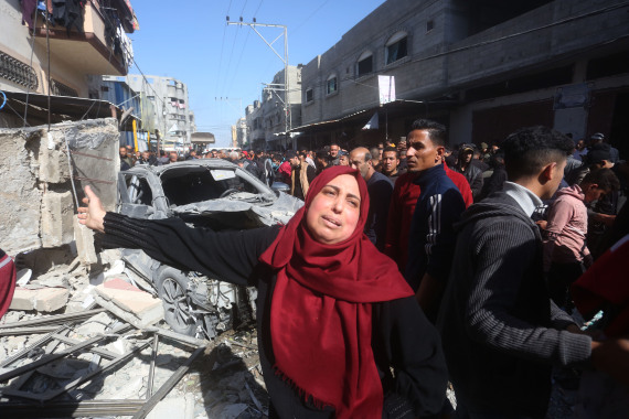 People gather in front of a building targeted by an Israeli airstrike in the southern Gaza Strip city of Rafah.jpg